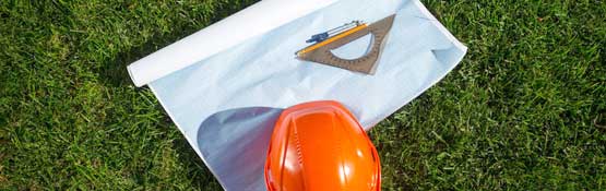 Hard hat and blueprints on grass